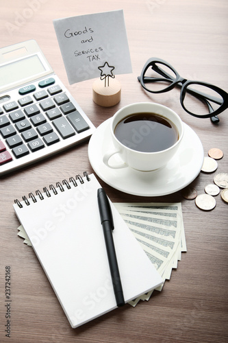 Inscription Goods and Services Tax with cup of coffee  notebook  calculator and banknotes