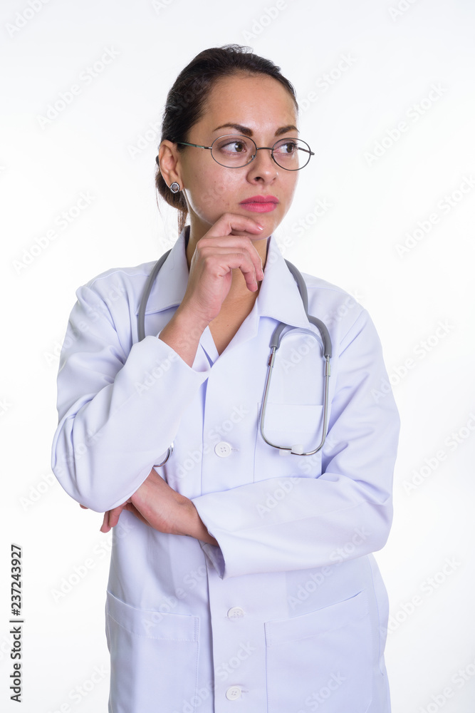 Studio shot of beautiful woman doctor thinking while looking at Studio shot of beautiful woman doctor thinking while looking at