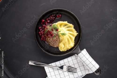 Fotografi Roast venison straight from the hunt with cranberry sauce on black background
