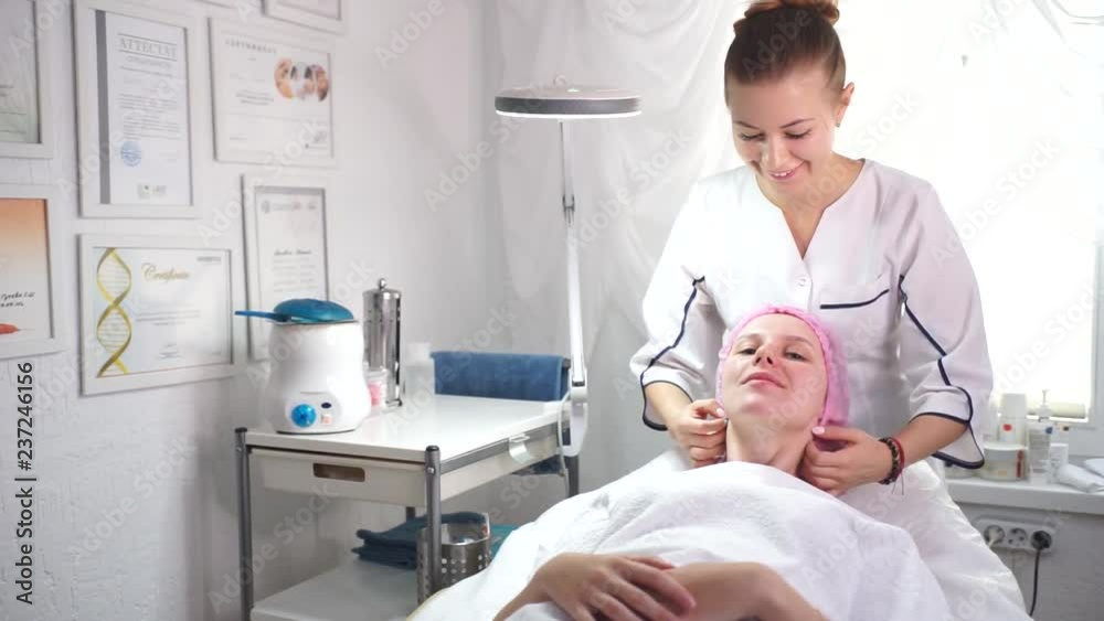 The beautician does the procedure of peeling the skin.young woman in a beauty salon.The beautician spreads the cream on the face of the client.Skin hydration for European girl. The beautician does the procedure of peeling the skin.young woman in a beauty salon.The beautician spreads the cream on the face of the client.Skin hydration for European girl.