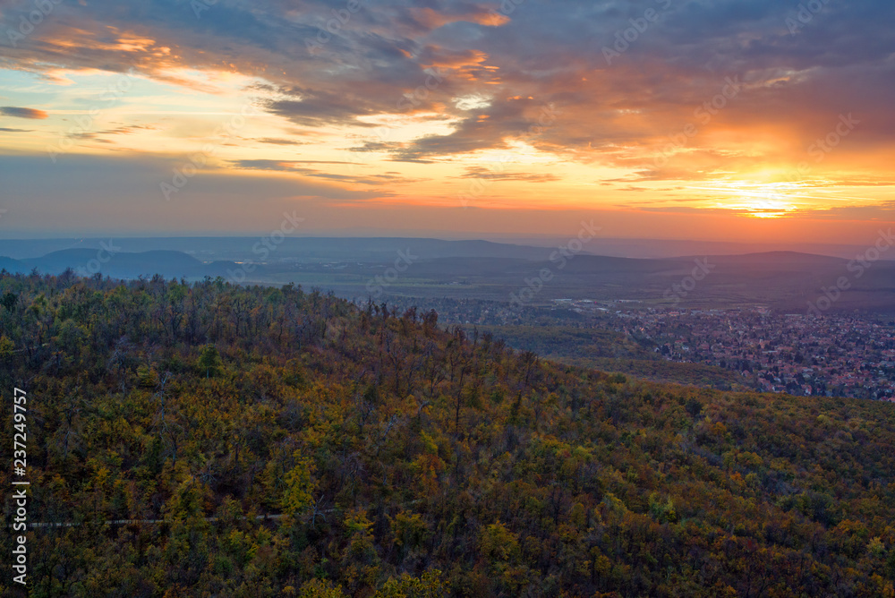Sunset over wooded hills and city suburbs in autumn. 