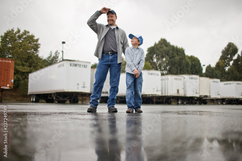 Young boy walking with his father standing in an outdoor freight yard. photo