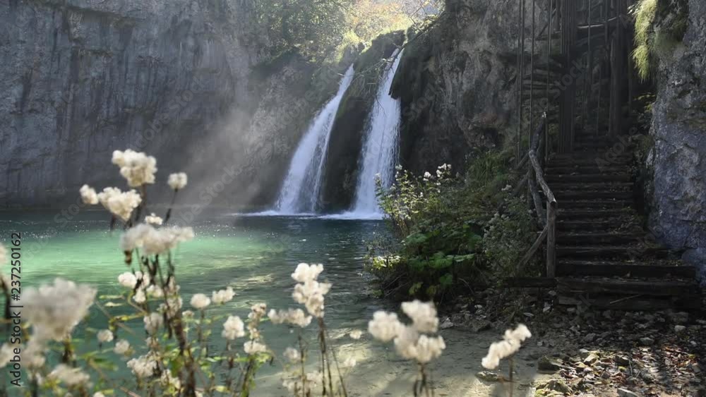 Amazing waterfall with pure blue water in Plitvice lakes. Orange autumn forest on background. Plitvice National Park, Croatia