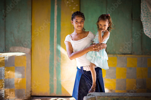 View of a teenage girl carrying her sister.