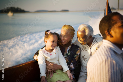 Mature adult couple sitting with their young granddaughter while on a boat. photo