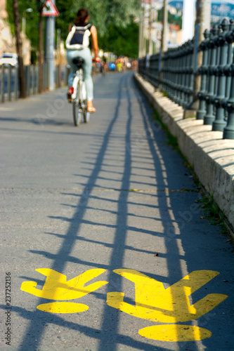 Yellow road marking for pedestrian on a sidewalk. Blurred bicyclist