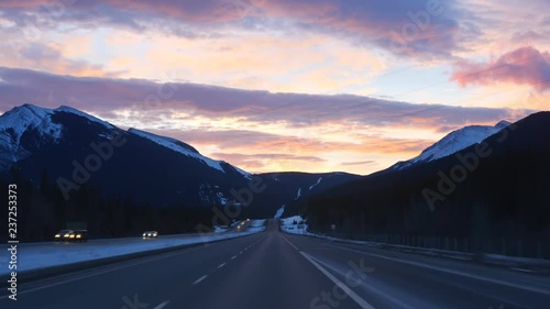 Sunrise on the TransCanada highway with snow covered Rocky Mountains. Passing traffic. Just east of the town of Canmore in Alberta, Canada. photo