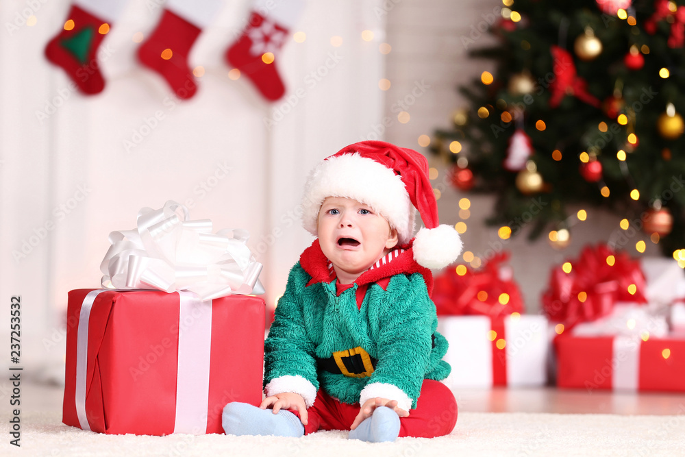 Little boy in christmas costume sitting on floor with gift box