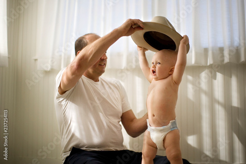 Mature man helping his baby son to put on a hat. photo