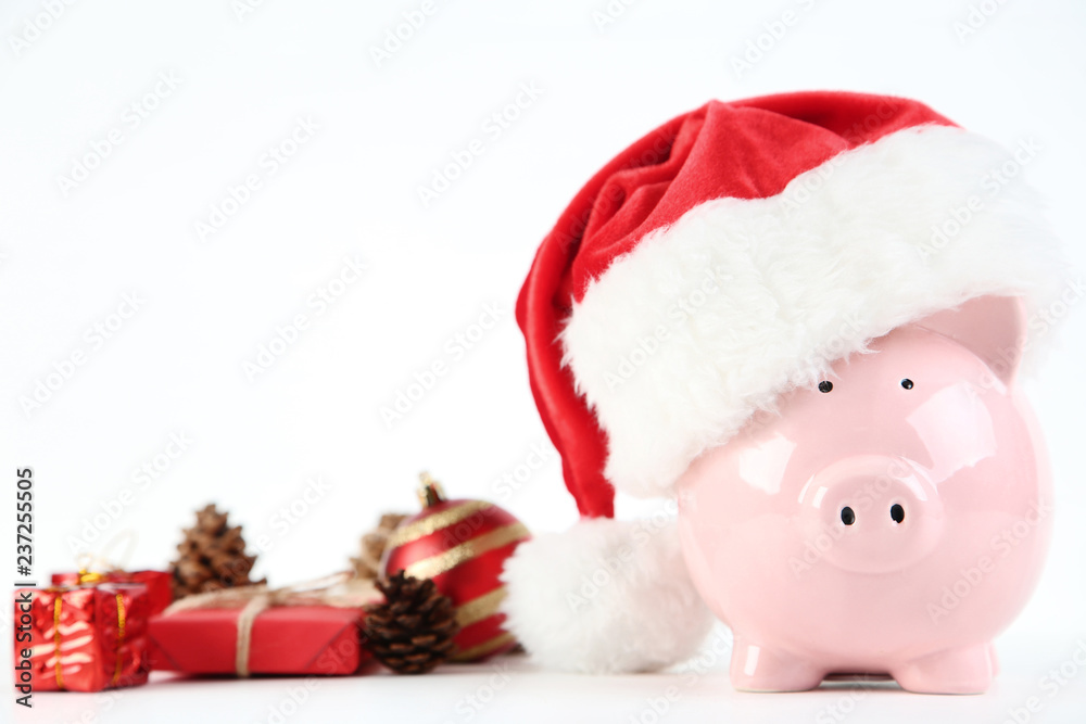 Pink piggybank in santa hat with christmas decorations on white background Pink piggybank in santa hat with christmas decorations on white background