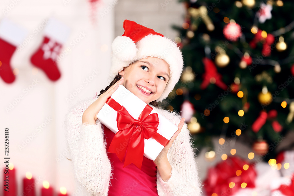 Young girl with gift box near christmas tree at home