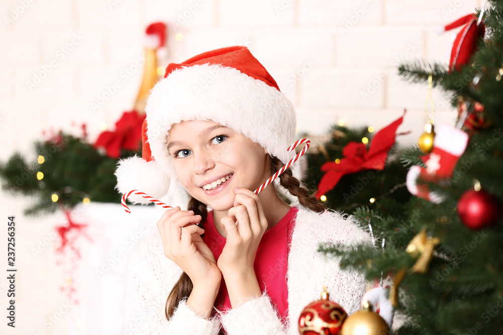Young girl with candies near christmas tree at home Young girl with candies near christmas tree at home