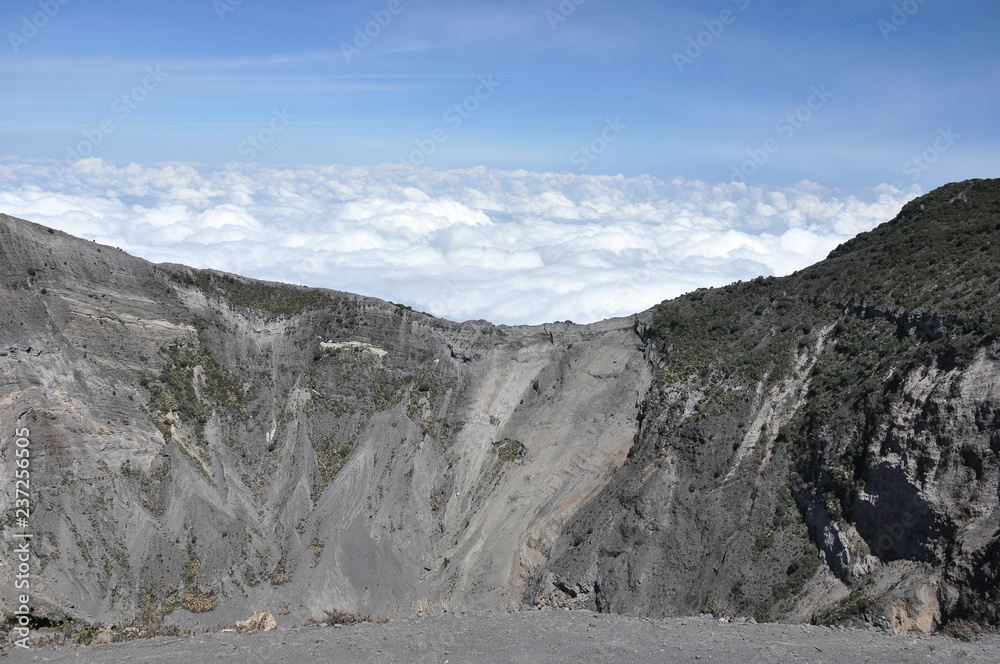 Irazu volcano in Costa Rica. Crater in clouds with protective barriers. Fragments of lava and pumice.