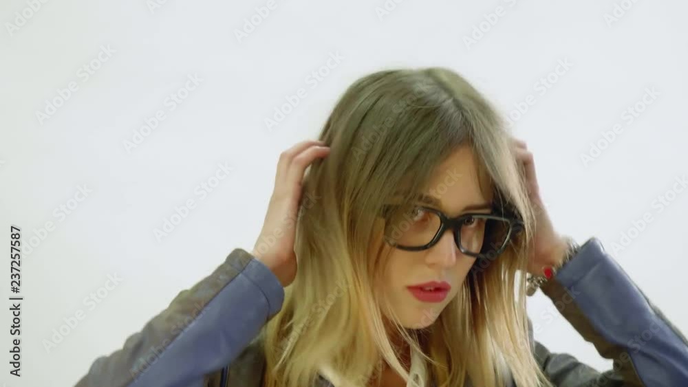 Young woman in balck jacket, cap and glasses poses during photo session
