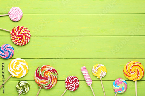 Colorful lollipops on green wooden table