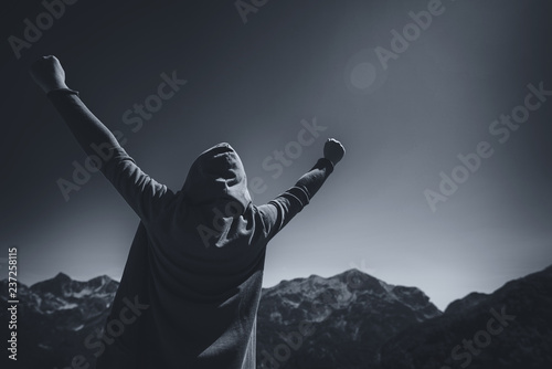 Happy female traveler with hands raised at mountain top