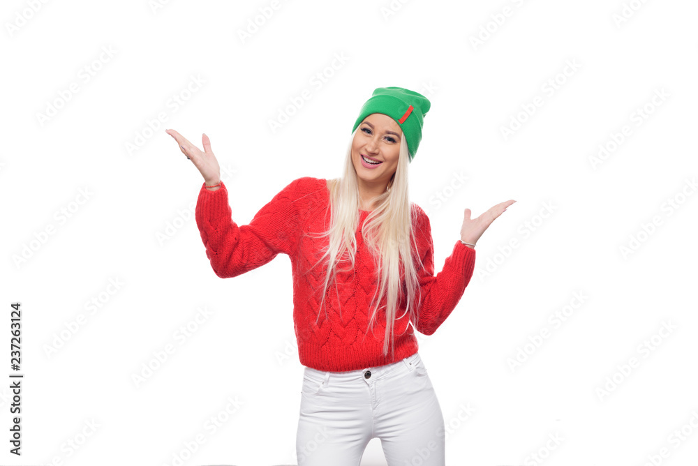 Fashion blond woman wearing bright knitted green hat and red sweater having fun over isolated white background Fashion blond woman wearing bright knitted green hat and red sweater having fun over isolated white background