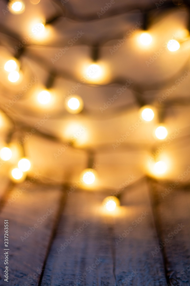 Defocused christmas background. Bokeh lights over wooden wihte rustic planks.