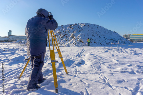 Surveyor conducts surveying in winter at a construction site