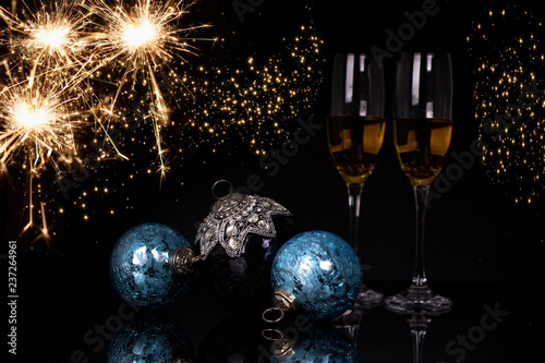 Two glasses champagne, sparkler and Christmas ornaments