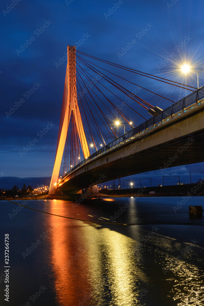 Illuminated cable stayed bridge over Martwa Wisla river at night in Gdansk. Poland Europe