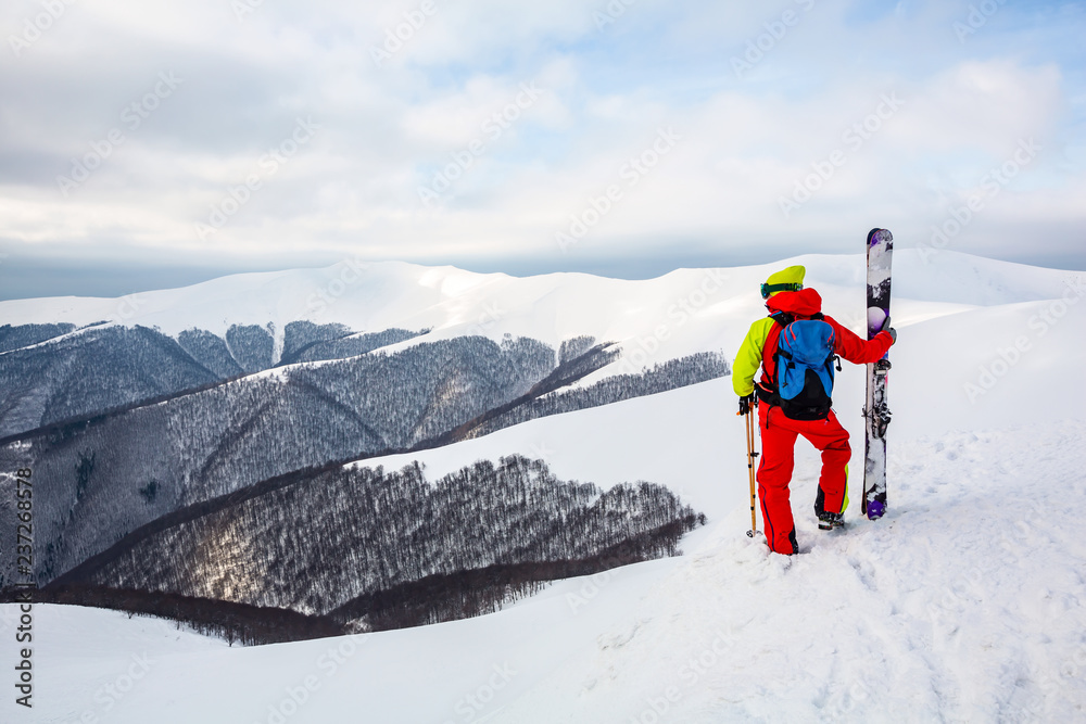 A skier is standing on the slope, watching the mountain scenery