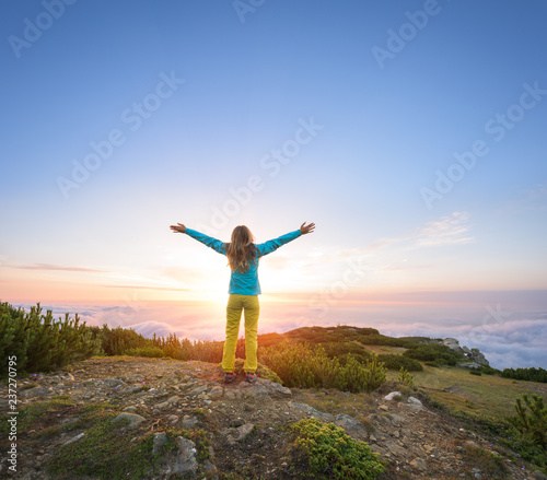 Woman expressing her inner joy in majestic landscape during sunset