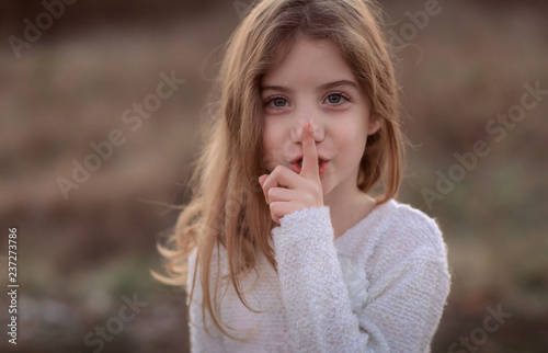 Cute little child with finger on lips making a silent gesture. Shh concept, be quiet