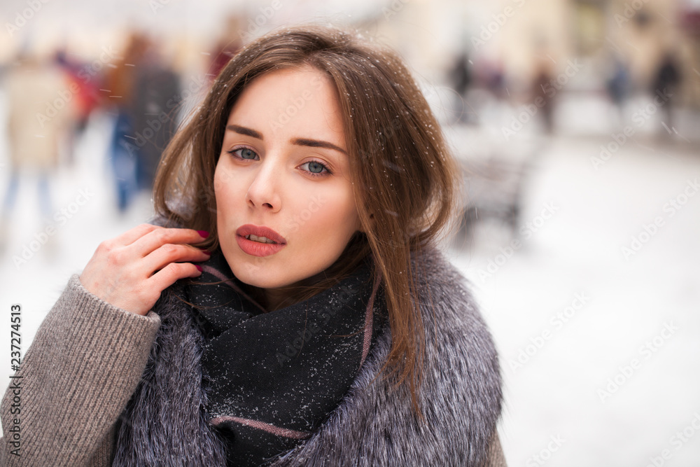 Young brunette woman in a gray coat with a fur collar