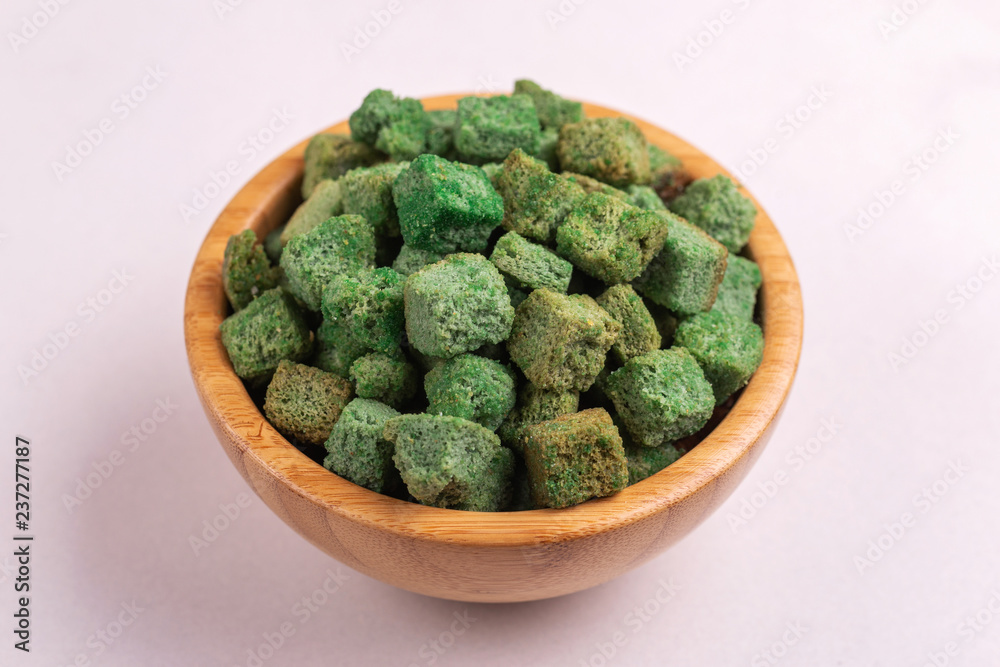 Wasabi flavored crackers in wooden bowl on light marble background