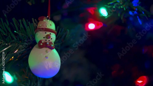 Snowman Ornament Hanging in a Christmas Tree with Lights Flickinger Behind it photo