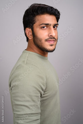 Portrait of young handsome Indian man against gray background © Ranta Images