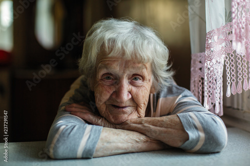 Portrait of a pensioner russian woman sitting at the table in home.