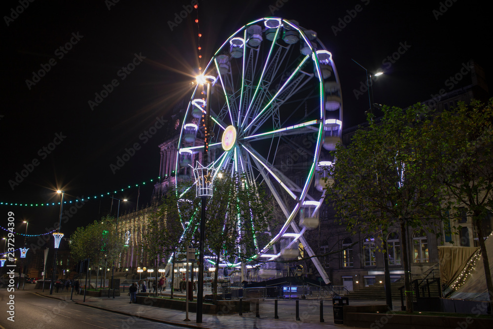 Long exposure photo of the Leeds Christmas ferris wheel that is outside the Leeds Town Hall and Leeds Library in the Leeds City Center West Yorkshire UK