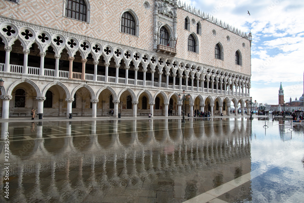 Venice, Italy - November 27, 2018: St. Marks Square (Piazza San Marco) during flood (acqua alta) in Venice, Italy. Doge's Palace in St Mark's Square flooded with reflection in Venice.