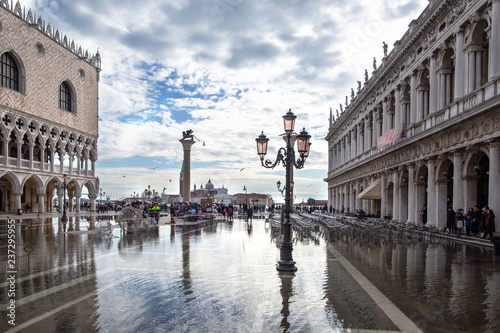 Venice, Italy - November 27, 2018: St. Marks Square (Piazza San Marco) during flood (acqua alta) in Venice, Italy. Doge's Palace in St Mark's Square flooded with reflection in Venice.