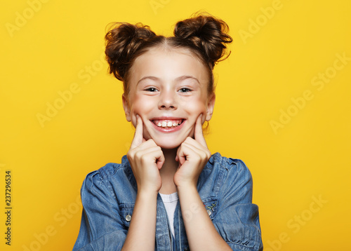 Portrait of cheerful smiling little girl on yellow background 