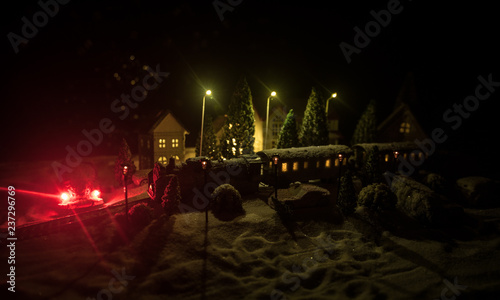 Miniature of winter scene with Christmas houses, train station, trees, covered in snow. Nights scene. New year or Christmas concept.