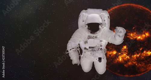 Fototapeta Naklejka Na Ścianę i Meble -  Astronaut in outer space near the Sun of solar system with reflection in helmet. Science fiction wallpaper. Elements of this image were furnished by NASA.