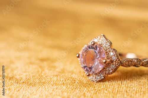 Jewelry pink diamond ring on golden fabric background close up