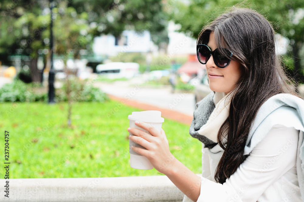 Woman holding paper coffee cup in the street. Woman holding paper coffee cup in the street.