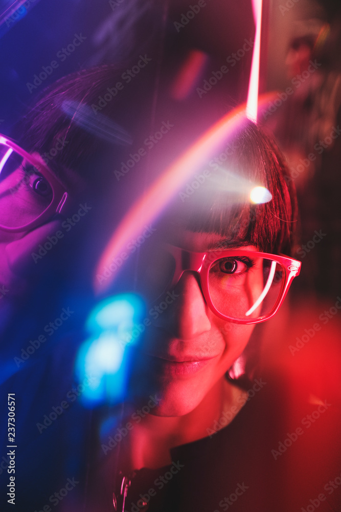 © Luca Pierro/Stocksy - Portrait of a young woman with mixed artificial light and reflections in Soho, London