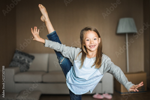 Cheeky little girl practicing gymnastics in her living room.