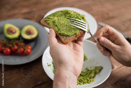 Valokuva Hands of cook chef preparing healthy avocado sandwich on dark rye toast bread ma