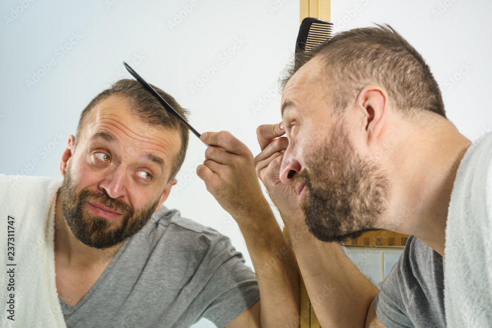 Obraz premium Man using comb in bathroom