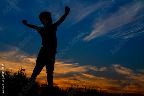 Silhouette of happy kid and beautiful sky in the evening