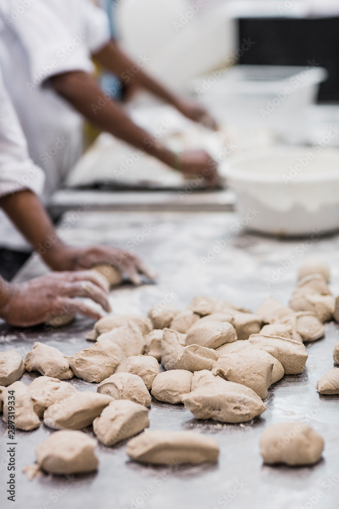 Two bakers making bread rolls in commercial bakery Two bakers making bread rolls in commercial bakery