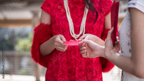 Close up Asian woman in chinese dress give the red envelope called angpao. Happy chinese new year concept