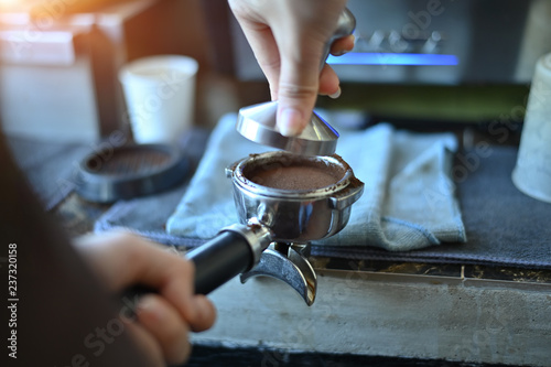 The process of making coffee step of cropped shot photo tamping freshly ground coffee beans in a portafilter.