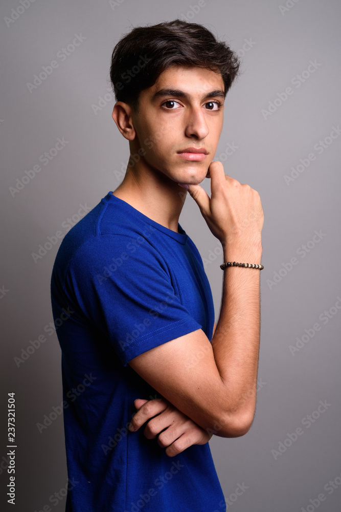 Young handsome Persian teenage boy against gray background Young handsome Persian teenage boy against gray background